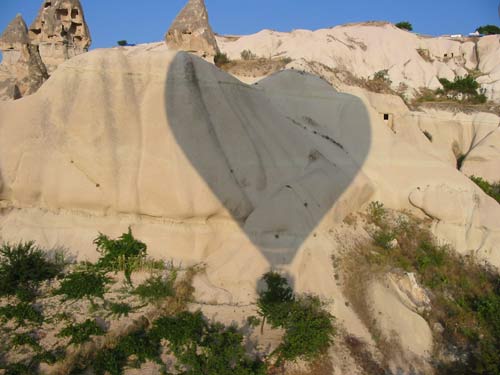 Balloon casting a love-heart shaped shadow on the rocky hills