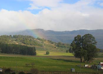 A rainbow lands on green fields.